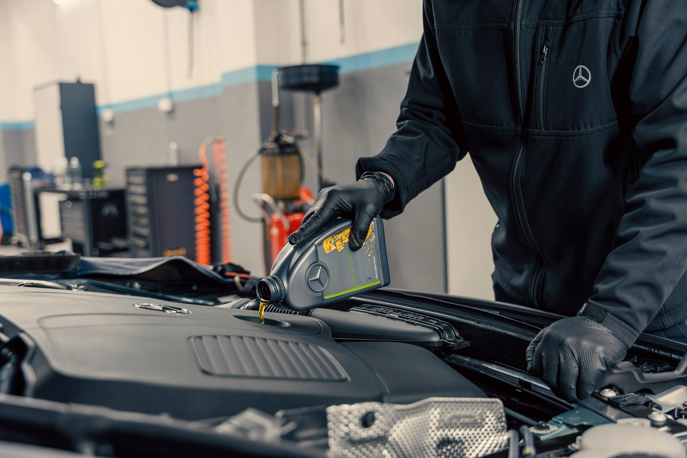 Car engine bay with tools including a screwdriver, ratchet wrench, and ignition coil on the engine cover.