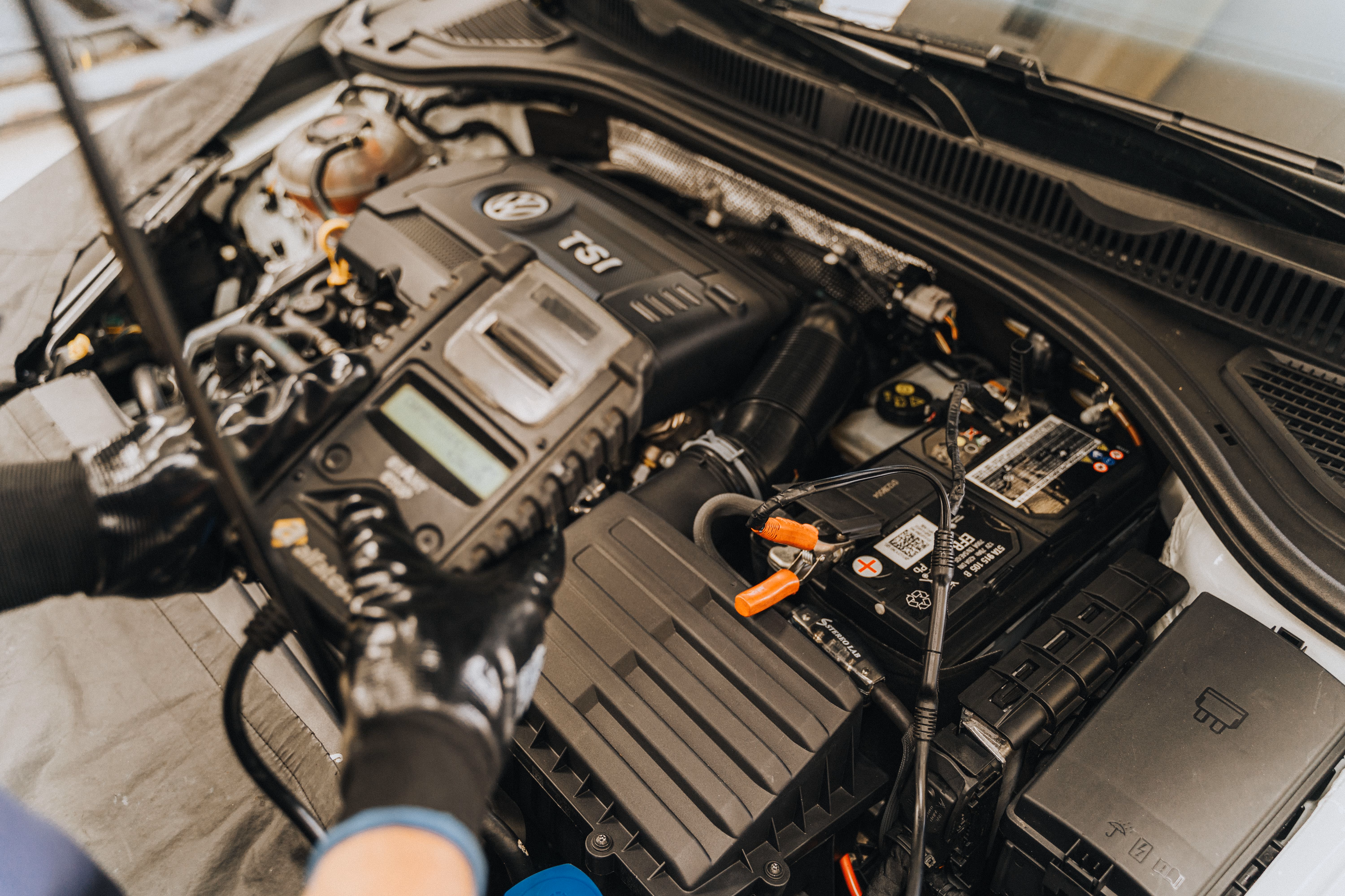 Technician testing a Volkswagen TSI engine with diagnostic equipment inside the car engine bay.
