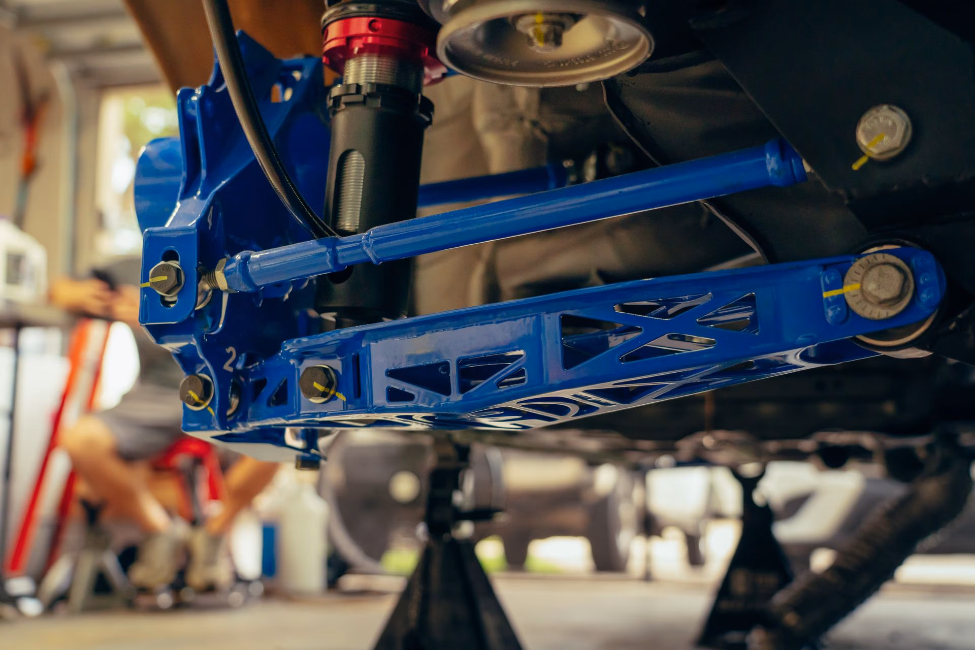 Close-up of a blue car suspension system installed under a vehicle in a garage.