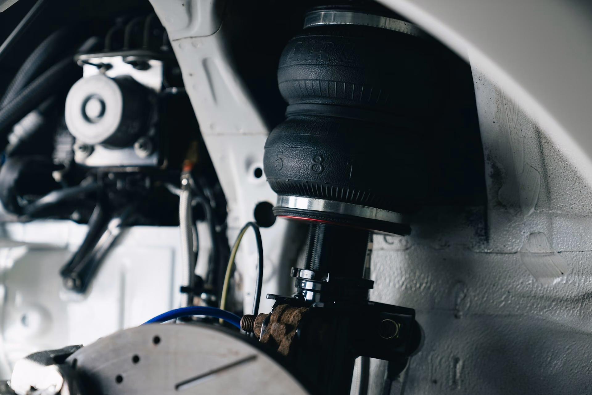 Close-up of a car suspension system showing an air spring and brake rotor inside the wheel well.